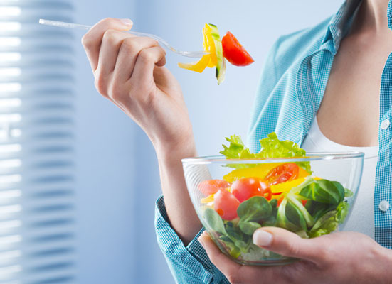 Woman eating salad out of a bowl in her hand