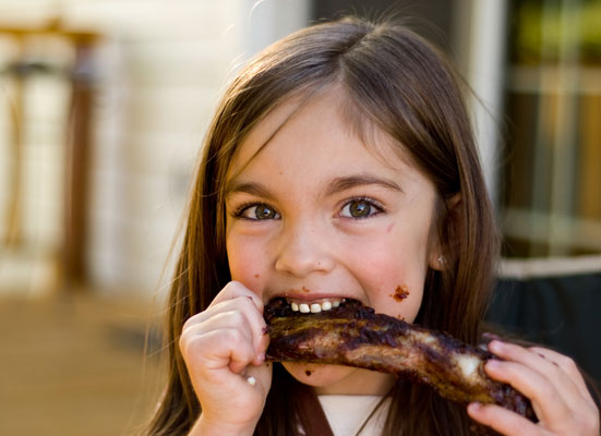 Girl eating meat with BBQ sauce